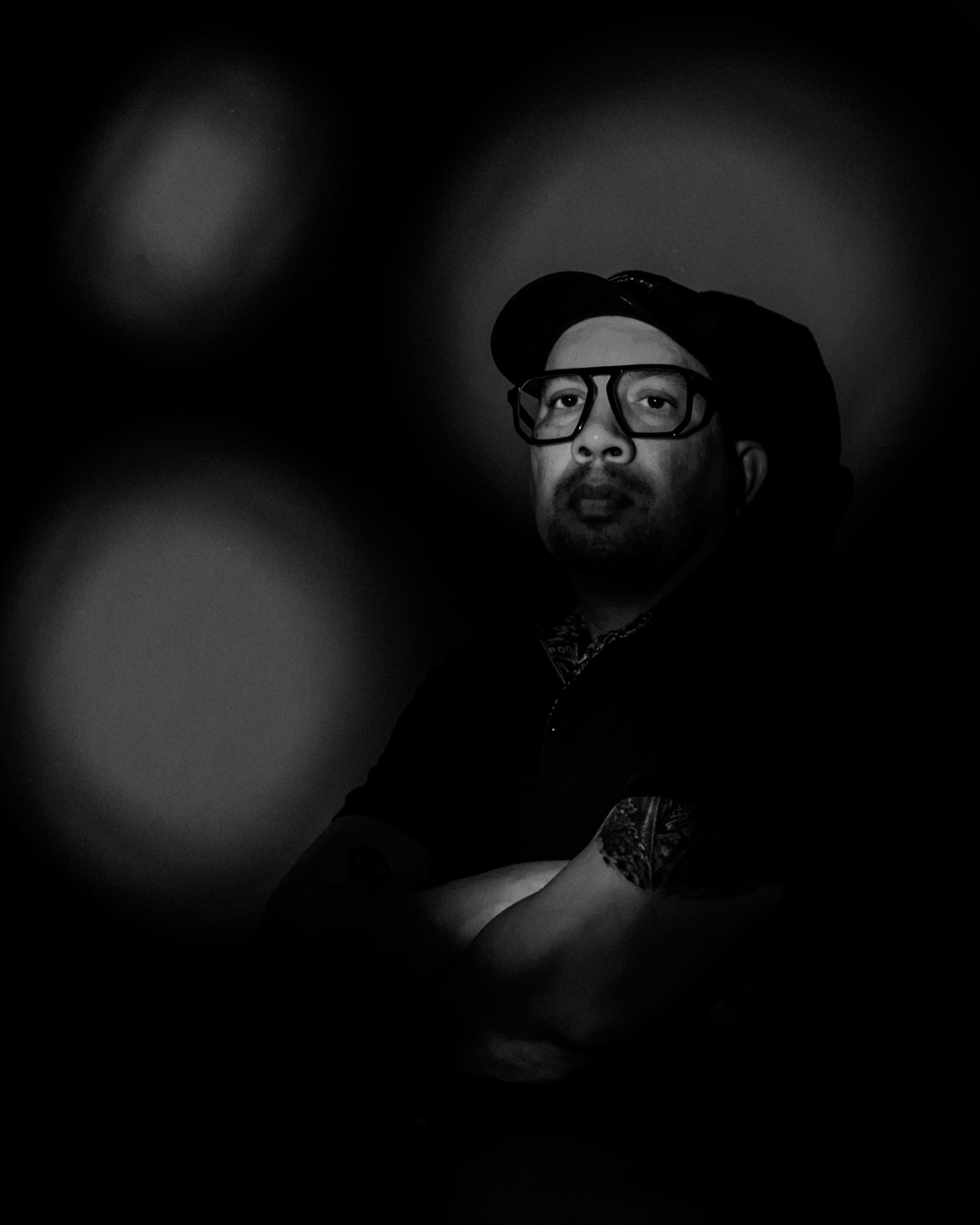 Juan C Muñoz, retratado en blanco y negro con gorra y gafas, entre luz y sombra.
