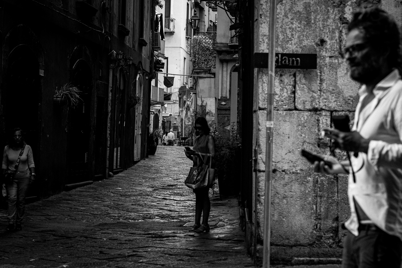 Varias personas en un callejón, con un hombre desenfocado en primer plano.